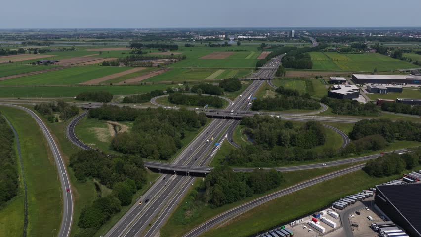 Aerial view of a highway interchange with cloverleaf ramps surrounded by green fields and trees in Utrecht, Utrecht, Netherlands.