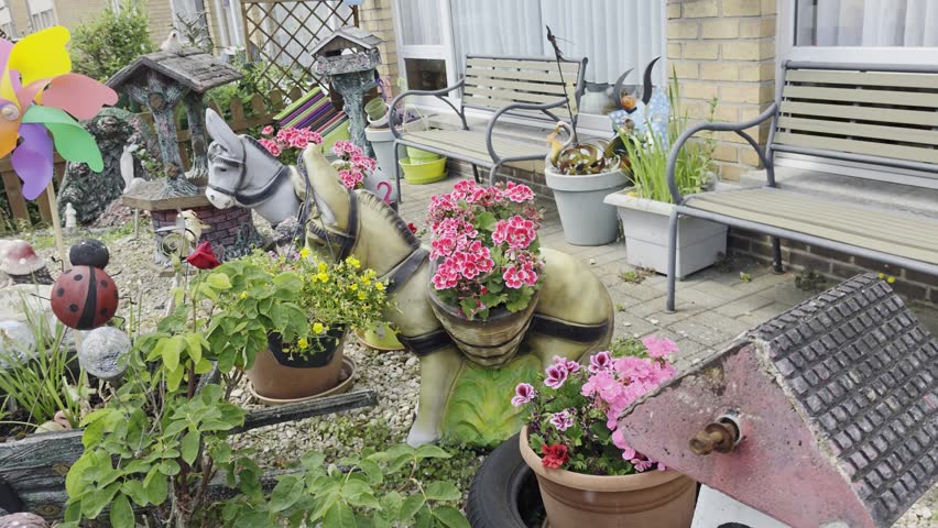 Colorful front yard garden decoration with flowers, donkey statues and a wind spinner