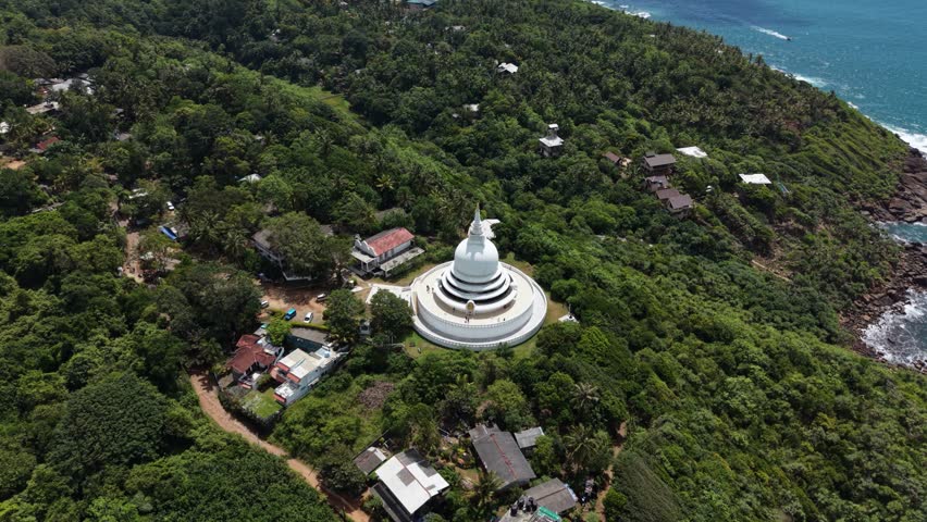 Aerial view of the white Japanese Peace Pagoda - Rumassala surrounded by dense tropical forest and coastal greenery in Unawatuna, Southern Province, Sri Lanka.