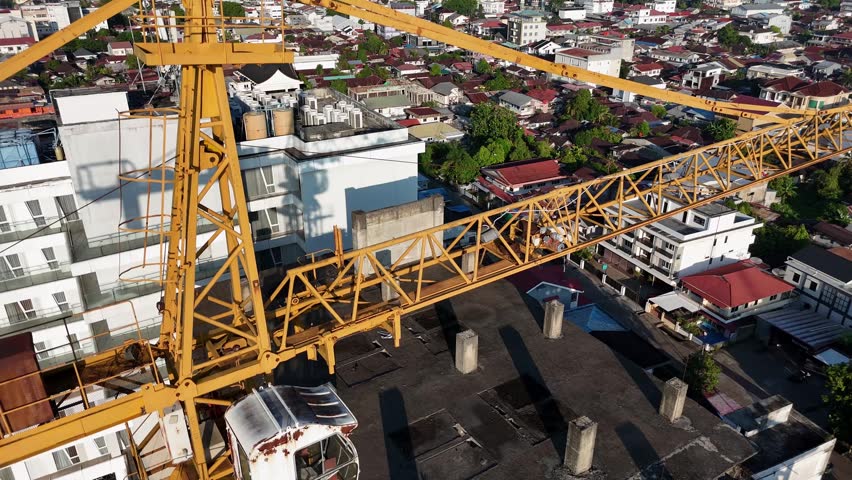 A yellow tower crane cabin atop the city