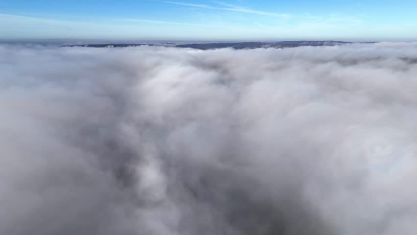 Aerial view of thick white clouds covering the landscape under a clear blue sky in Tubingen, Baden-Wurttemberg, Germany.