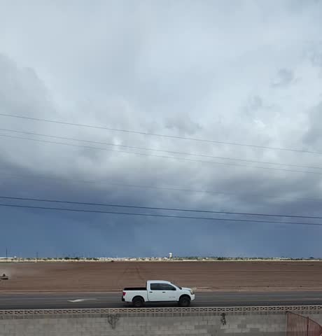 A dramatic monsoon storm moves across the foothills near Yuma, Arizona, as dark clouds roll over active agricultural fields. Strong desert winds sweep through the farmland while tractors continue working beneath the approaching storm. Captures the powerful contrast between Southwest desert weather and Arizona farming life.