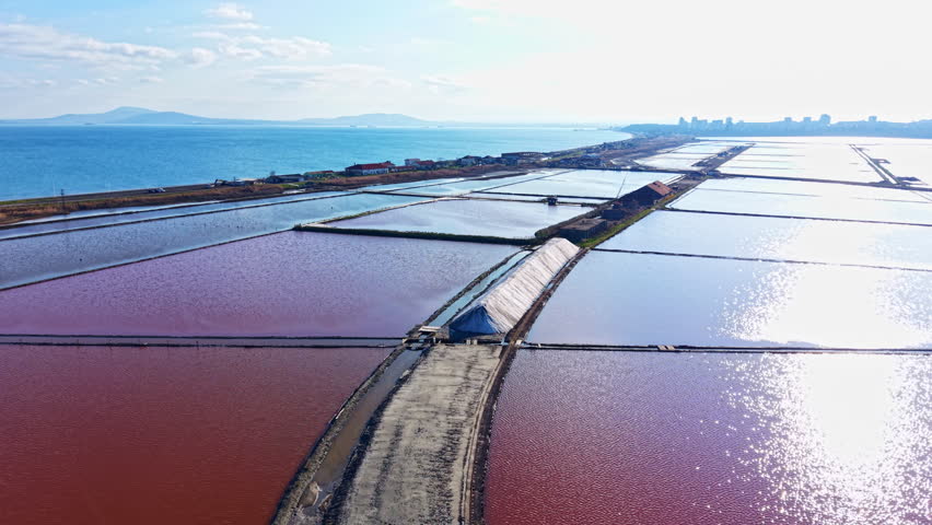 Surreal scenes unfold as sunlight dances on crimson waters of a salt marsh, reflecting the horizon