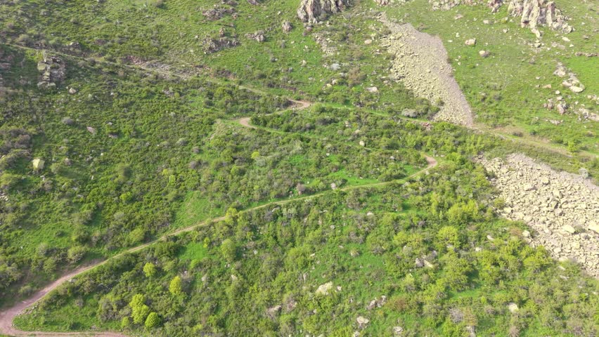 Aerial View of Winding Mountain Trail Through Green Hillside