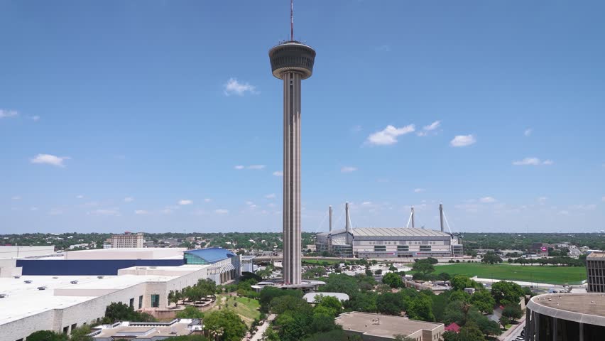 The HemisFair tower, aka Tower of Americas, towers over the Alamodome in downtown San Antonio as a drone tracks sideways along US Highway 281. Henry B. González Center is also visible from the aerial.