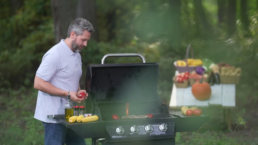 Backyard grill with rest. Man cooking tasty barbeque. Barbeque scene with middle-aged cook. Backyard barbeque. Man relaxing on picnic barbeque by nature.