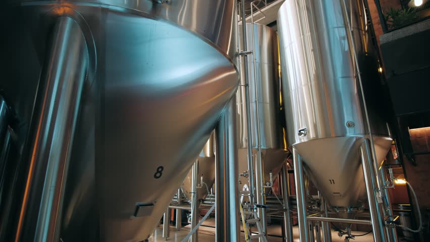 Steel fermentation tanks and brewing equipment inside a modern craft brewery production facility.
