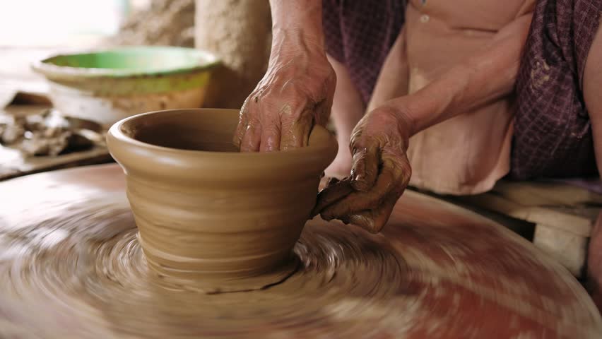 Potter hands shaping clay bowl on spinning pottery wheel in a vietnamese workshop for creating traditional ceramics.