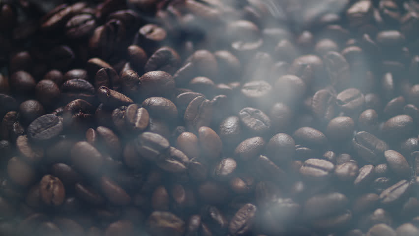Smoking hot fragrant roasted coffee beans. Hot steaming high quality roasted dark coffee beans. Smoke coming from perfect brown coffee seeds. 
