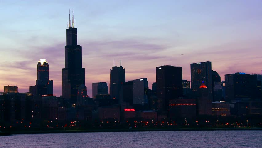 Dusk aerial view of Chicago skyline, famous Willis Tower skyscraper, Lake Michigan water, city lights twinkle, urban landscape, nightfall.