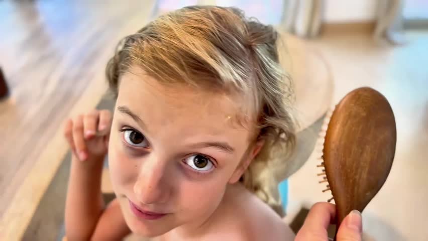 A high-angle, close-up shot of a young blonde girl smiling gently as an adult