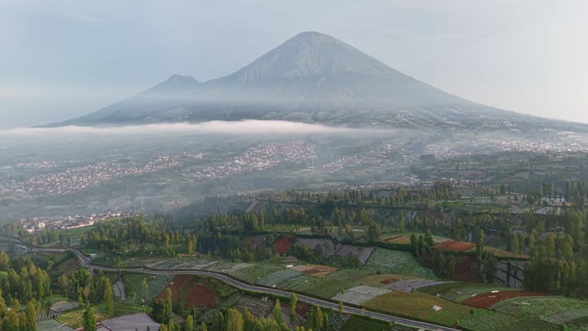 Mountain landscape with highway and agricultural fields, green plantations and scenic rural environment.