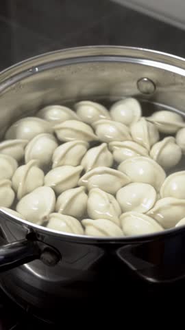 Dumplings are cooked in boiling water. The process of making homemade meat dumplings. Frozen dumplings are dropped into boiling water, stirred, and brought to a boil. Homemade semi-finished products