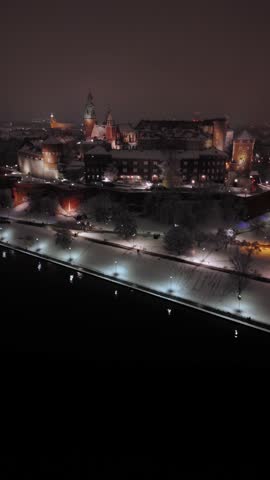 An aerial flyover of Wawel Castle in spring, covered in snow, on an evening in Poland.