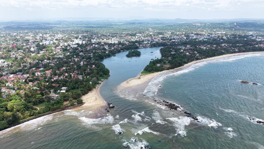 Aerial view of the Nilwala River mouth meeting the Indian Ocean with sandy beaches and lush coastal vegetation in Matara, Southern Province, Sri Lanka.