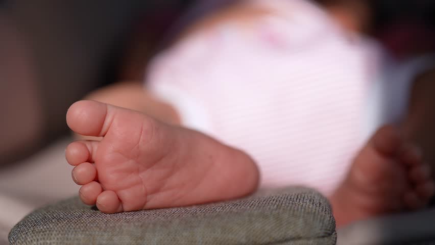 Extreme close up of cute newborn baby feet resting on a stroller cushion