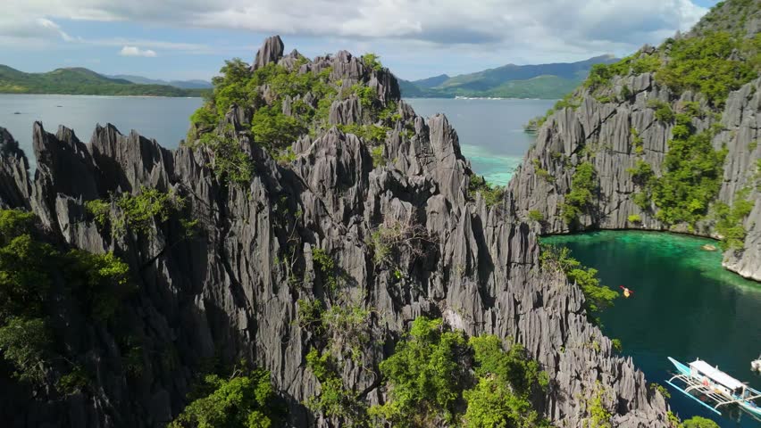 Aerial parallax of Twin Lagoon with dramatic limestone karst pinnacles and wooden walkway between turquoise lagoons in tropical paradise of Coron Palawan Philippines