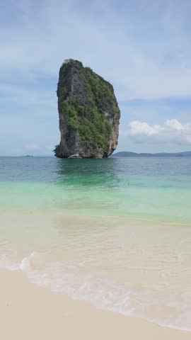 Ko Poda in Krabi Thailand, Isolated rock formation rises majestically from tranquil ocean blue sea, surrounded by white sandy beach and gentle waves under a clear sky