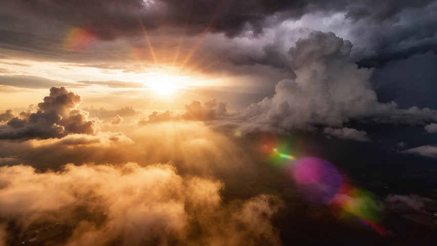 Flying over a panoramic sunset cloudscape, a beautiful aerial timelapse of animated cumulus clouds drifting as the golden sun breaks through with peaceful god rays, set against a dramatic stormy sky. Perfect for cinematic intros, inspirational backgrounds, meditation videos, spiritual visuals, and epic nature projects. This breathtaking aerial sky footage creates a peaceful, dreamy, and majestic atmosphere with golden sunlight, dramatic clouds, and heavenly scenery.