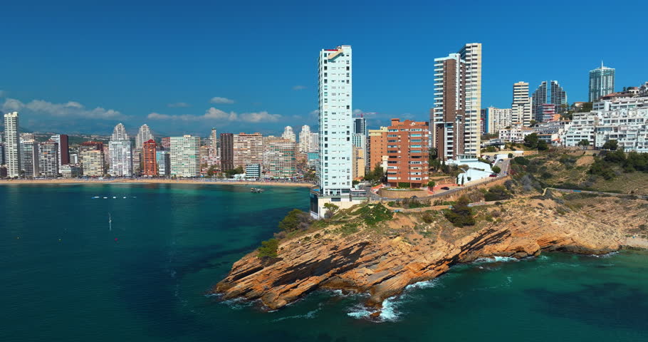Benidorm city resort skyscraper building rocky cliff coast line beach turquoise sea water drone aerial view spain mediterranean coastal landscape summer travel destination tourism hotels