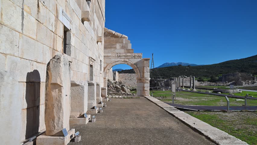 POV shot walking towards an arch at the ancient ruins of Patara, a Lycian city in Turkey. Sunny day view of the archaeological site