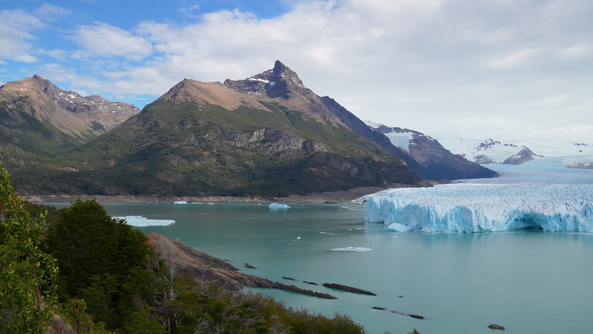 Panoramic view of the Perito Moreno Glacier in Argentina. Massive blue ice wall meeting the turquoise water of Lake Argentino with mountains in the background