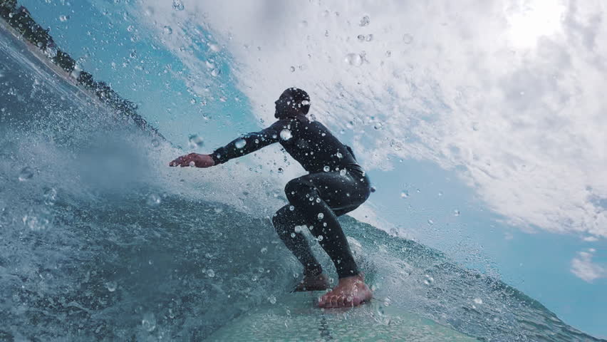 Man surfs the ocean wave. POV in water and underwater footage of the male surfer riding the wave