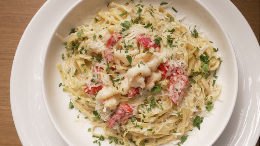 Creamy shrimp pasta with tomatoes and herbs served on a white plate in a restaurant, fa01