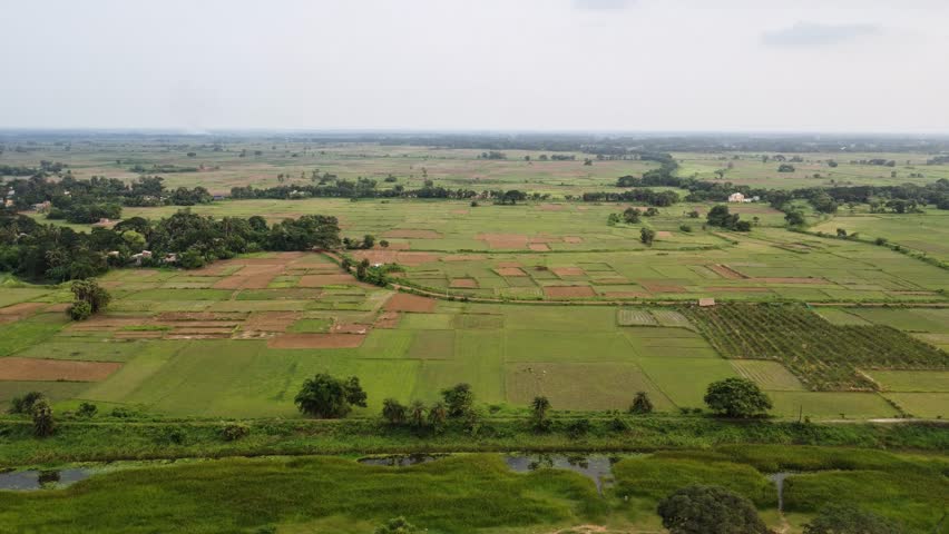Aerial View of Patchwork Agricultural Fields and Green Farmlands in Rural Countryside. High Angle Panoramic Shot of Scenic Green Meadows and Cultivated Lands under Overcast Sky.