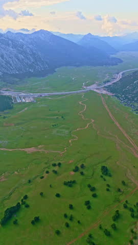 Aerial drone view of green fields and a river running through a rural mountain valley in Turkiye.