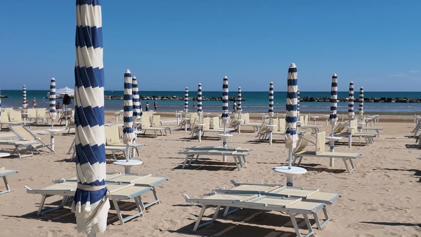 Sunny sandy beach ready for summer season, with umbrellas closed and no people. Senigallia, Ancona, Marche, Italy. Adriatic Sea