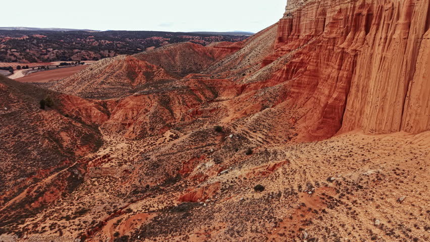 The view captures a canyon with steep rock walls and dry land. The clouds are present in the sky above. The scene shows the natural beauty of the outdoor setting.