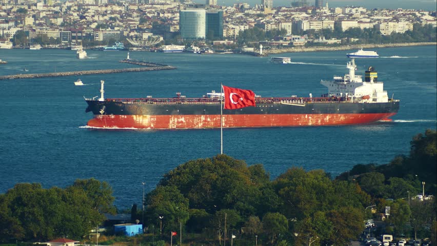 A large industrial oil tanker entering the Bosporus Strait from the Sea of Marmara past a waving Turkish flag towards Kadikoy in Istanbul, Turkey. Telephoto lens shot from Topkapi Palace