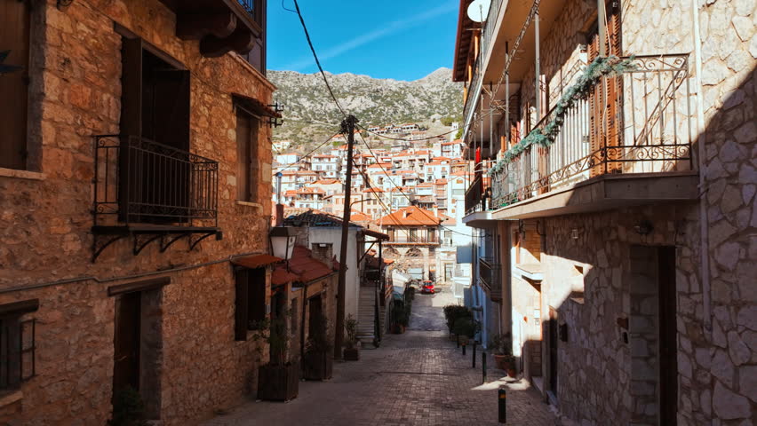 Traditional stone hotels and balconies under a clear sky in the town center of Arachova, Greece
