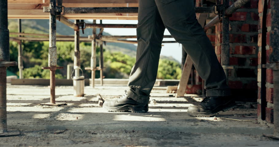 Walking, legs or worker by scaffolding at construction site, infrastructure evaluation or inspection. Feet, risk assessment or person with check for worksite safety, property or building progress