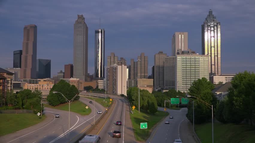 Dynamic aerial footage of Atlanta cityscape, skyscrapers and busy highway traffic, urban development, city transit motion.