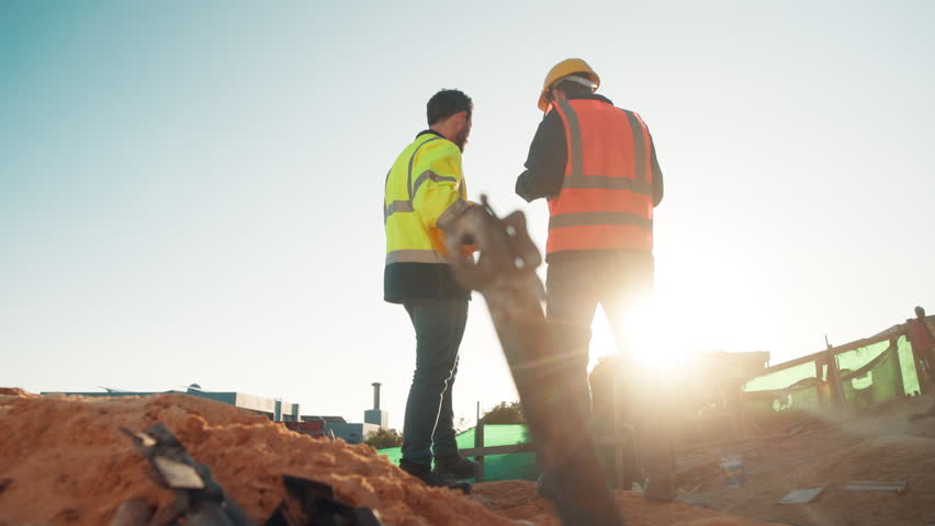Men, team and meeting on construction site for planning, building development and space. Low angle, engineers and outdoor with discussion for inspection requirements, renovation progress and back