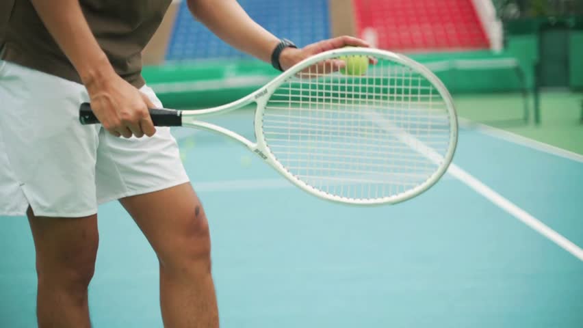 Closeup of a tennis player holding a racket on a blue court