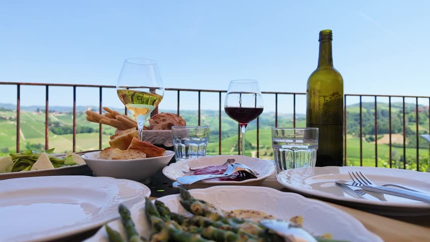 A scenic al fresco lunch with wine and bread overlooking rolling green vineyard hills.