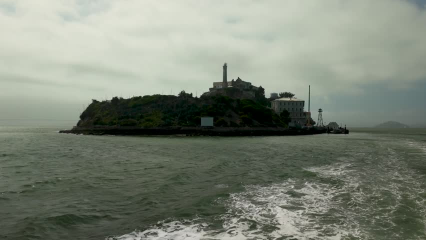 Sailing away from Alcatraz Island, the prison fades into fog and distance behind the boat. San Francisco skyline grows closer as wind fills the sails. Tourists look back at the rocky cellhouse, carrying stories of escape and isolation home.