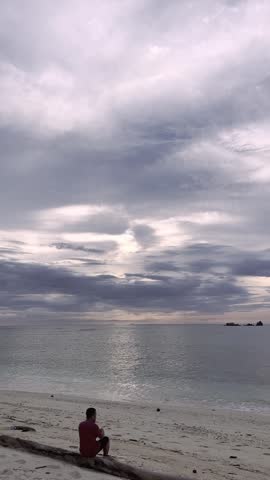 Man Sitting on Beach Looking at Ocean