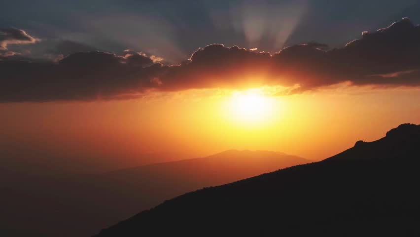 Timelapse cinematic golden sunset mountains sun rays piercing clouds dramatic sky silhouette nature landscape spiritual hope inspiration light rays wilderness horizon outdoor vista. Gods suns eye