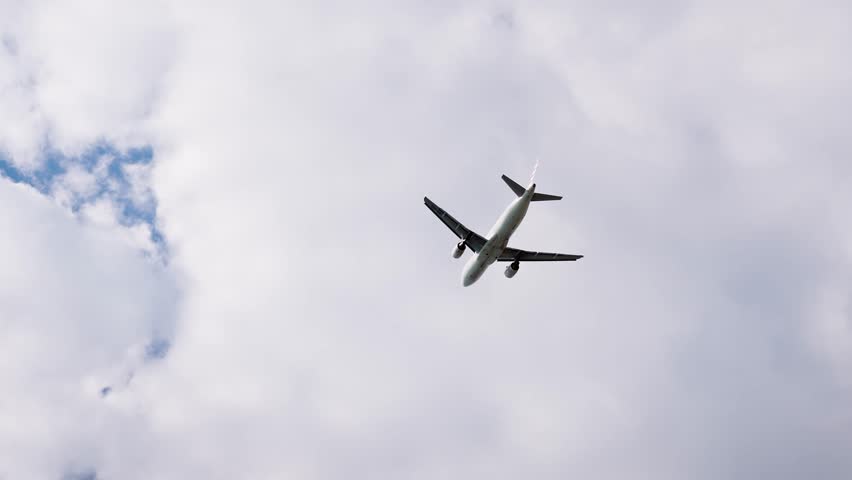 Low angle view of a commercial airplane flying across a clear blue sky, capturing modern air travel, freedom and transportation in motion