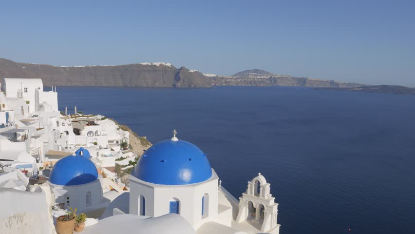 Blue domed church with water horizon and caldera view in Oía, Santorini, Greece.