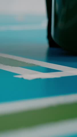 Close-up of a worker applying green epoxy resin on a blue floor using a paint roller