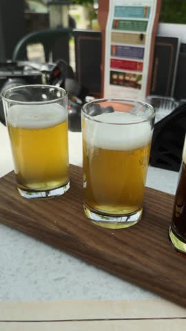 Selection of craft beers served in tasting glasses on a wooden paddle at a cafe table. Beverage tasting concept for hospitality, tourism and leisure