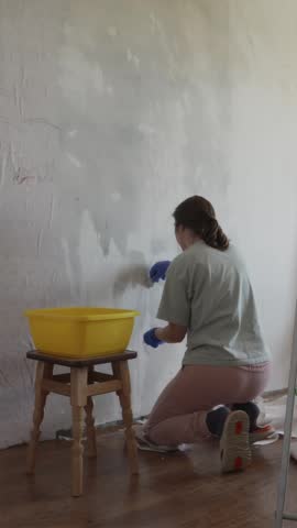 Vertical portrait of a happy girl initiating a DIY redecoration in her newly bought house. Concept of real estate ownership, youth financial success, and independent life.
