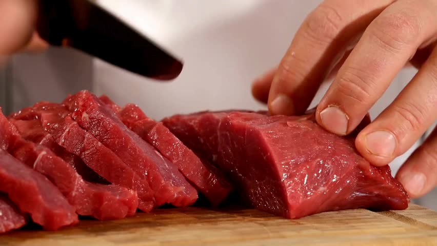 An experienced chef skillfully cuts raw meat. He uses a big and strong knife to cut the meat perfectly. Every cut is neat and consistent. 2K 60fps