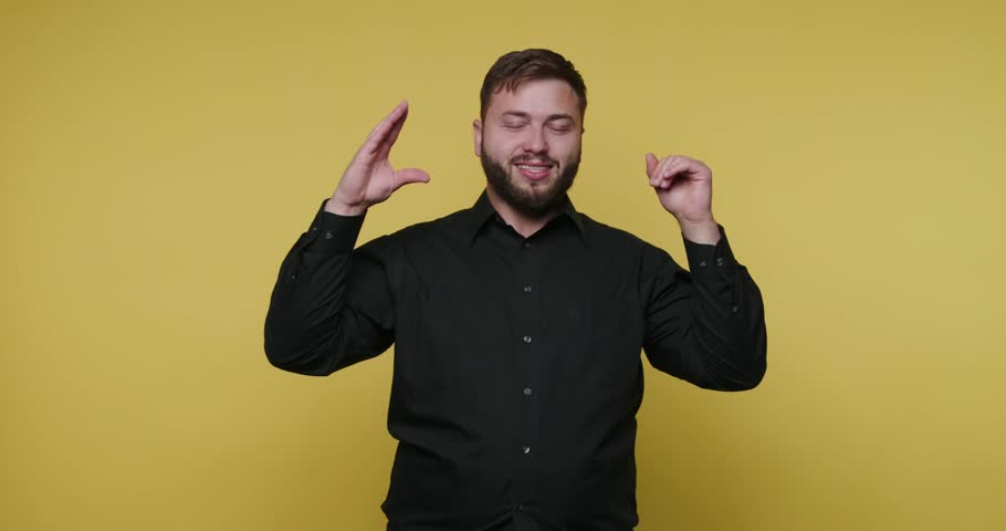 A man is using sign language to express thoughts and ideas. He makes different hand signs and gestures as he communicates. The background is bright yellow.