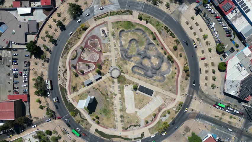 High aerial drone view showcasing Guadalajara city, Mexico. A bustling urban scene with vehicles navigating the iconic Normal Traffic Circle roundabout.